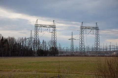 Electrical substation with high voltage power lines and pylons under cloudy s Stock Photos