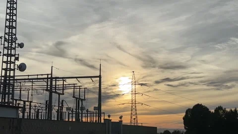 Electrical substation power lines silhouetted at sunset with moving clouds Stock Footage 326790183