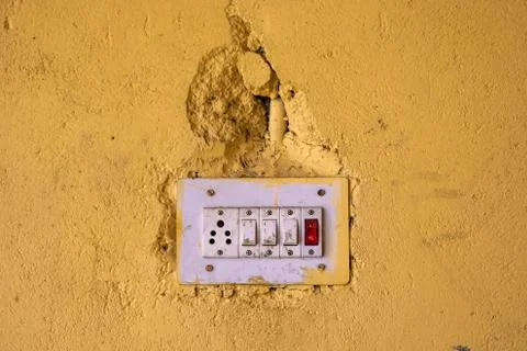 Electrical switch and plug on dirty yellow wall. Stock Photos