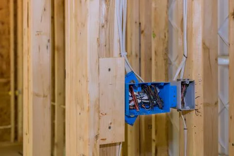 Electrical switch box is plastic a has wires attached to its wooden frame beams Stock Photos