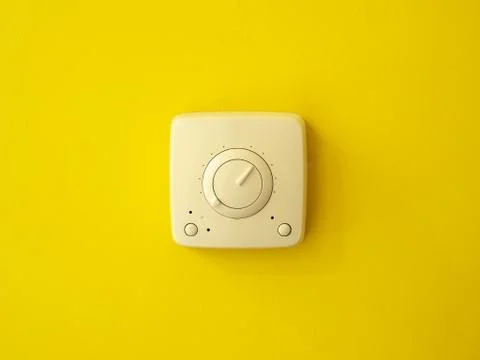An electrical switch in the center on a yellow wall. Frontal view. Stock Photos