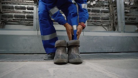 Electrical technician is putting on special protective shoes. Stock Footage 115428370