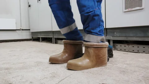 Electrical technician is putting on special protective shoes in power station. Stock Footage 142950218