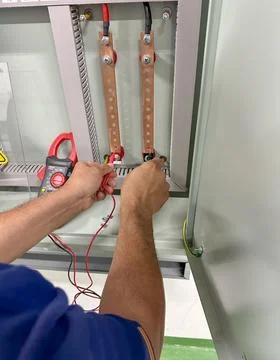 Electrical technician using a digital multimeter to measure voltage inside an Stock Photos