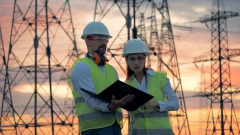 Electrical transmission lines and two technicians working with a laptop near Stock-Footage 101199059