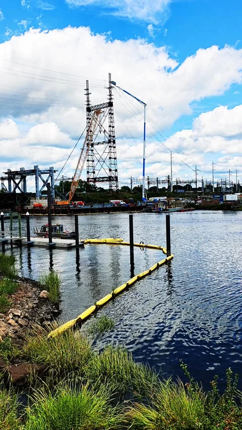 Electrical transmission tower under construction by river 스톡 동영상 344814040