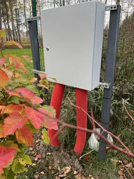 Electrical utility box mounted on metal supports with bright red conduits Foto stock