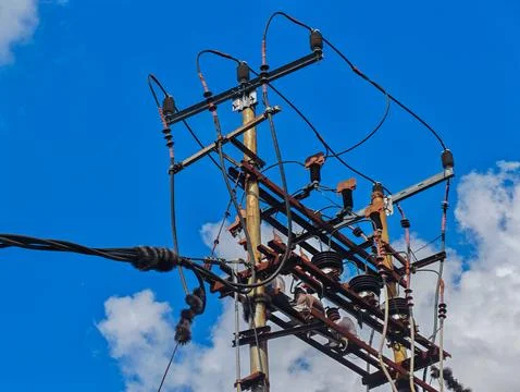 Electrical Utility Pole with High Voltage Power Lines Against Blue Sky Foto stock