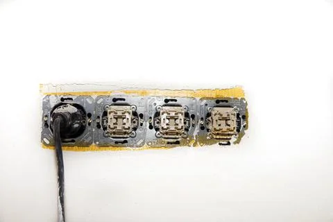 Electrical wire and opened plug socket on the old plastering wall Stock Photos