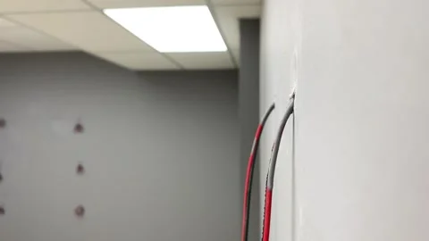 Electrical wire cable hanging from grey wall inside room close up. Panning shot Stock Footage 249806259