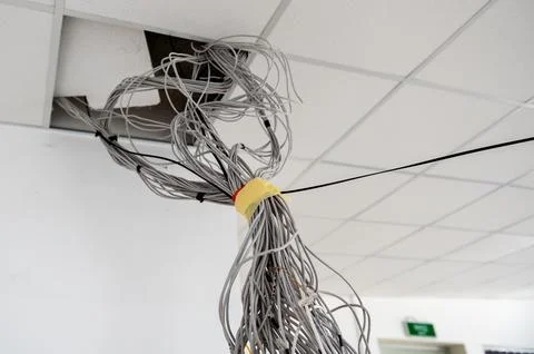 Electrical wires hanging from the ceiling. Cables hanging from ceiling of r.. Stock Photos