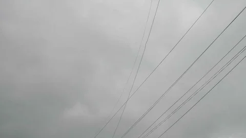 Electrical wires sway during stormy weather with grey sky behind Stock Footage 76899862