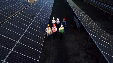 Electrical workers walking in between solar panels Stock Footage