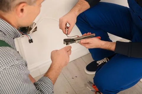 Electrician and apprentice working with wires indoors, closeup 스톡 사진