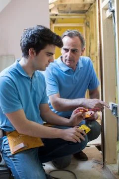 Electrician With Apprentice Working In New Home Stock Photos