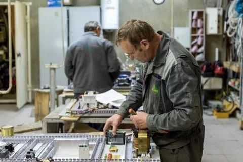 The electrician assembles and adjusts the electrical control panel. Works on Stock Photos