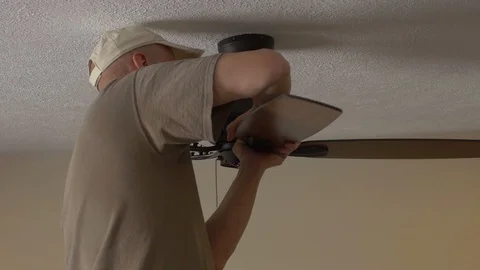 An electrician attaching blades while installing a ceiling fan Stock Footage 106793154