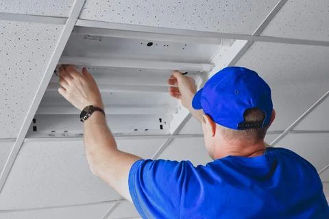 Electrician attending to the ceiling light panel installation in office Fotos Stock