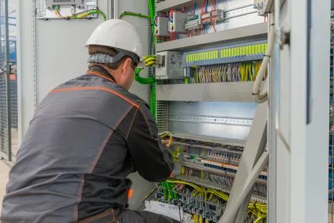 Electrician builder at work inspecting cabling connection of high voltage power Stock Photos