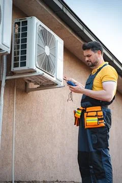 Electrician is checking an air conditioner with a multimeter Stock Photos