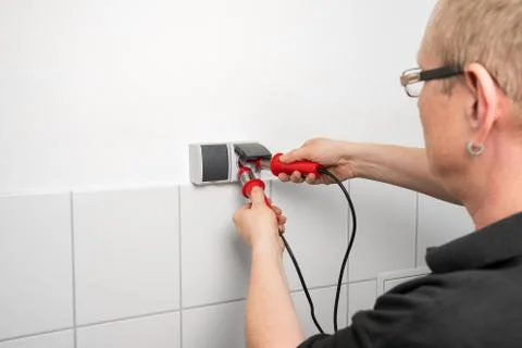Electrician checks a socket with a voltage indicator Stock Photos