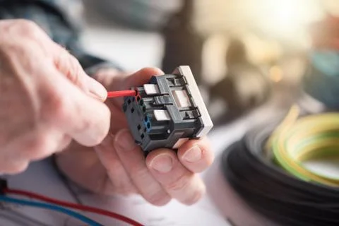Electrician connecting a wire into a power socket, light effect Stock Photos