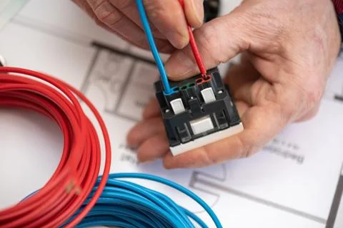 Electrician connecting a wire into a power socket Stock Photos