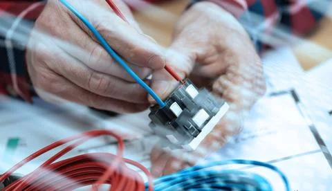Electrician connecting a wire into a power socket; light effect Stock Photos