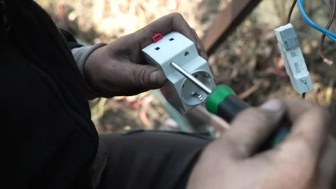 Electrician disassembles an electrical socket with a screwdriver Stock Footage 261178201
