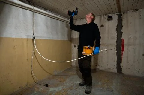 Electrician drilling ceiling while routing electric cable Foto stock
