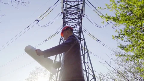 Electrician engineer looks at the electricity grid plan near the power lines Stock Footage 77699251