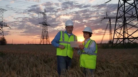 Electrician explains tasks to trainee with tablet near power transmission lines Stock Footage 282678282