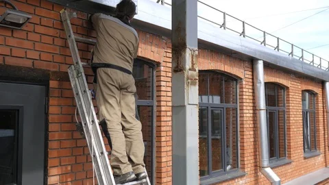 An electrician fixes the wiring while standing on the stairs of the house Stock Footage 107803095