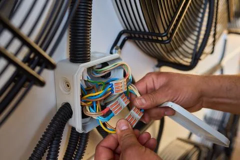 Electrician fixing complex wiring in junction boxes, showing expertise in e.. Stock Photos