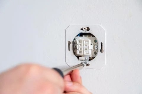 Electrician fixing electric socket with a screwdriver. Handyman working Foto stock