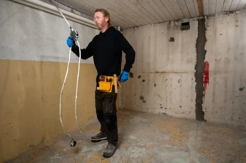 Electrician grabbing tool while working on electrical junction box Stock Photos