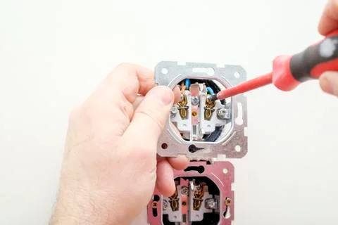 Electrician hand holds socket in process installation or repairing with apply Stock Photos