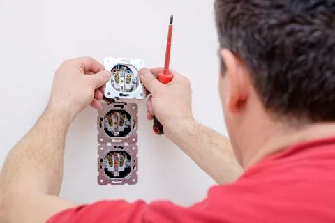 Electrician hand holds socket in process installation using screwdriver Stock Photos