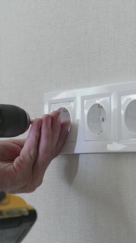 Electrician hands installing white faceplate frame over four wall sockets Video stock 345039340
