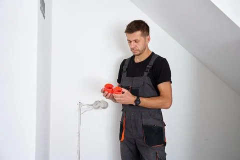 Electrician holding electrical boxes for wall sockets Stock Photos