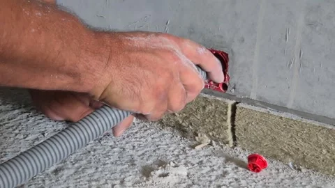 Electrician inserting flexible plastic conduit into flush mounted wall box Stock Footage 341510064