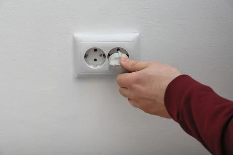 Electrician inserting plug into power socket on white background, closeup Stock Photos