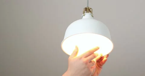 The electrician inserts a new light bulb into the lamp Stock Footage 220563894