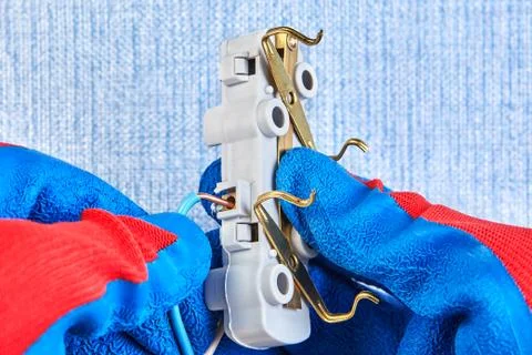 Electrician inserts wires in wall socket. Stock Photos