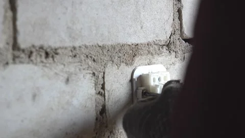Electrician installing electrical cable trunking on brick wall Stockbeeldmateriaal 333696081