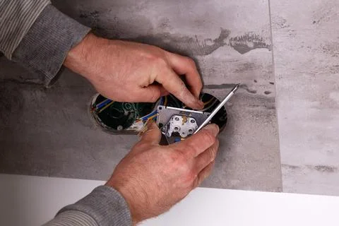 Electrician installing electrical outlets in a wall made of porcelain tiles. Stock-Fotos