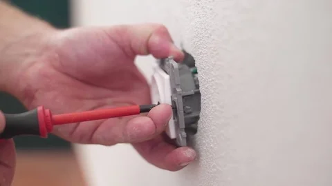 Electrician installing electrical socket with screwdriver in wall slow motion Stock Footage 80929383