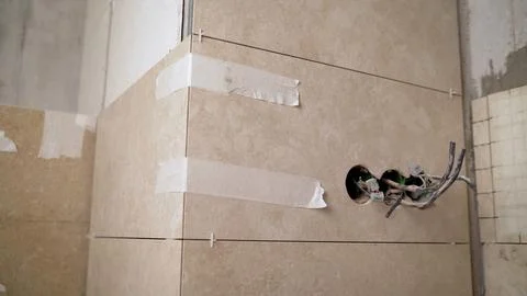 Electrician installing light switch and socket on bathroom tiled walls. Stock Photos