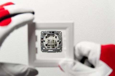 Electrician installing light switch on painted wall with screwdriver. Man ins Stock Photos