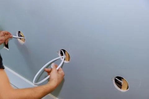 Electrician is installing a new current socket at the construction site of a new Stock Photos